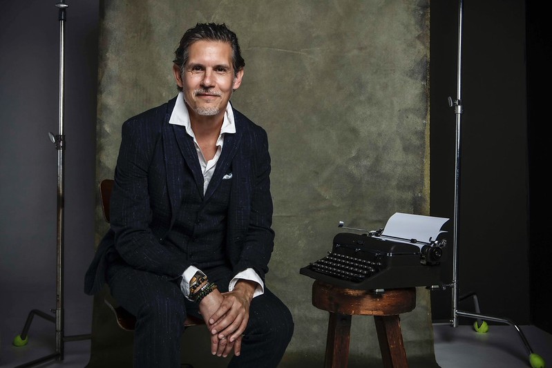 Patrick Combs seated beside a vintage typewriter