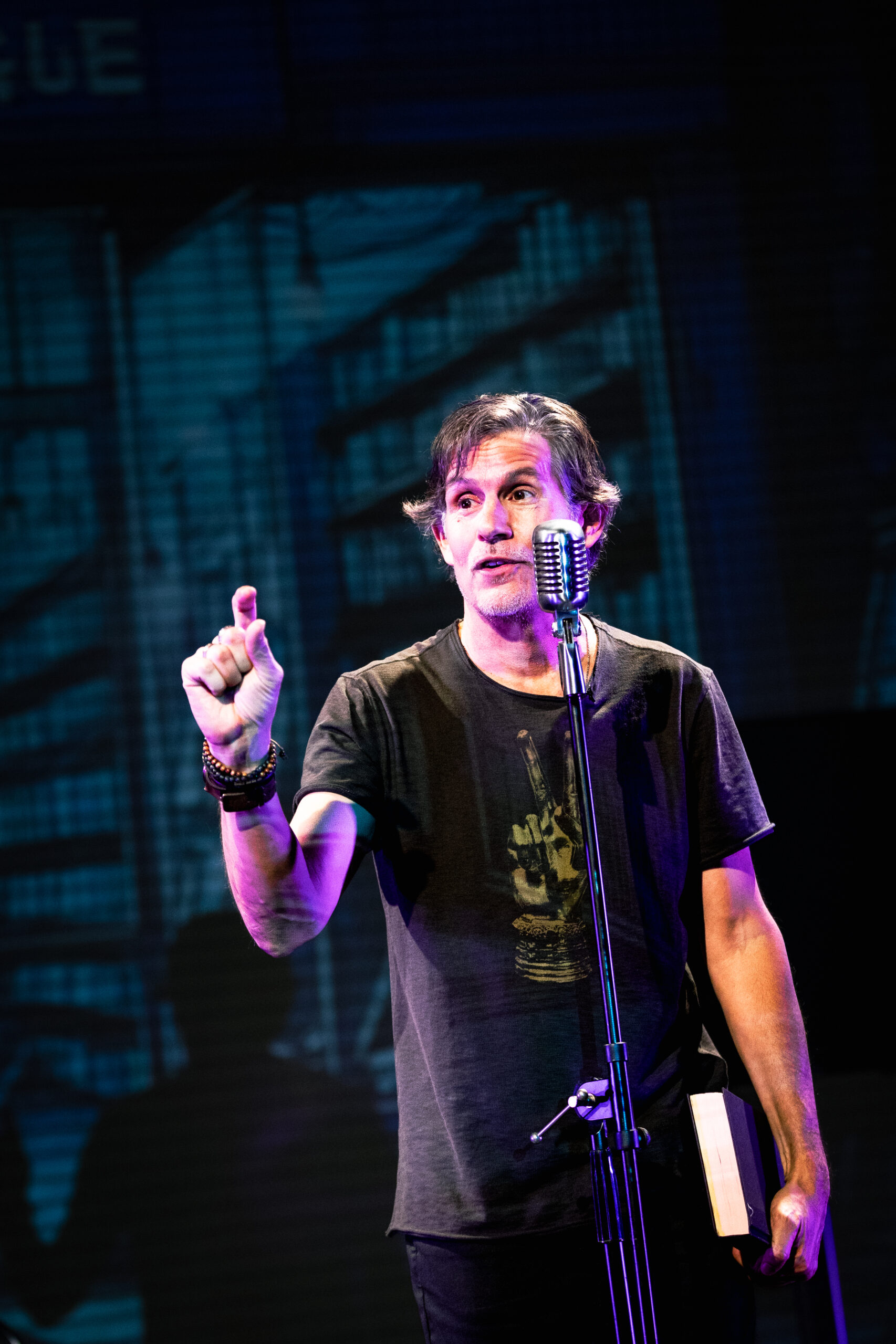 Patrick Combs performing Trying to Break A Leg, at vintage microphone with stage lighting